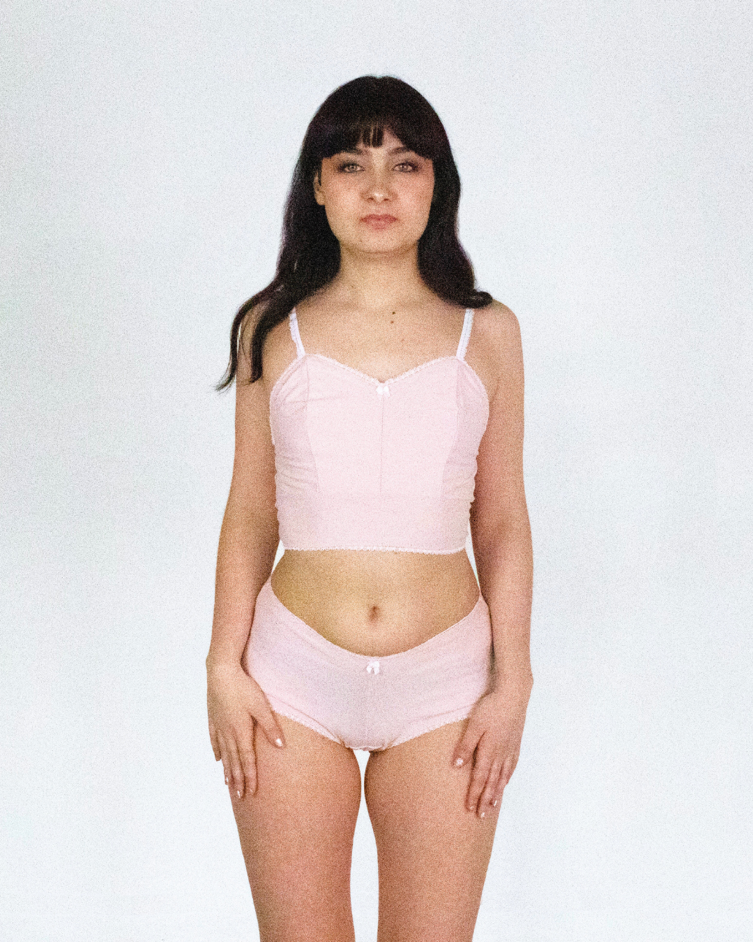 Model wearing a pink lingerie set on a white background